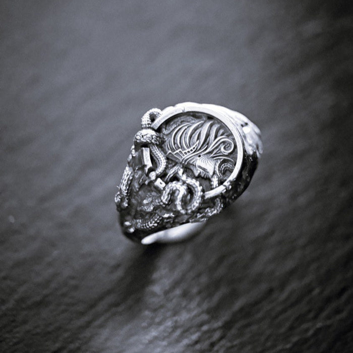 Medusa silver ring with intricate design on a dark textured surface